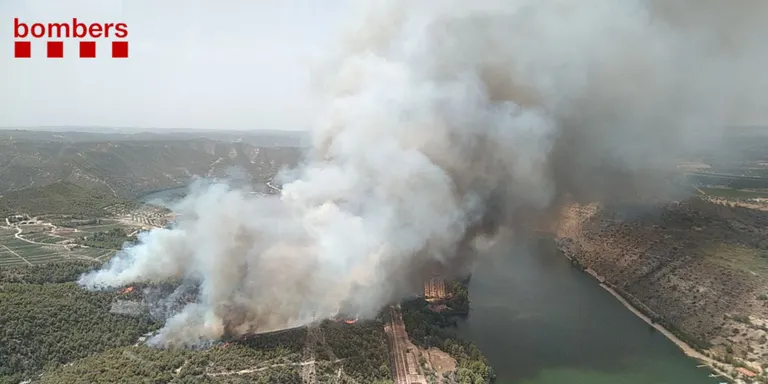 Els bombers treballen per evitar que el foc de la Pobla de Massaluca salti a l'altre costat del riu Ebre