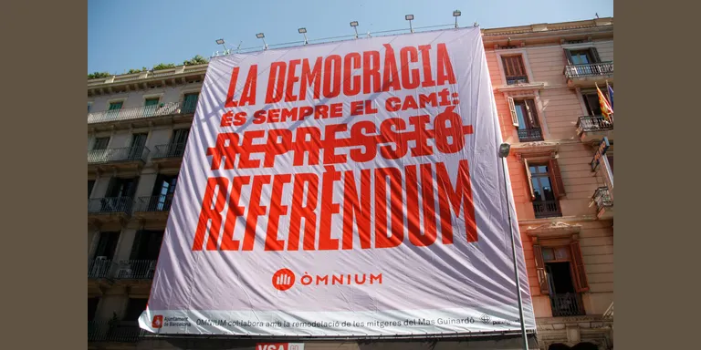 Òmnium desplega una pancarta al centre de Barcelona reclamant un referèndum a l'Estat: "La democràcia és el camí"