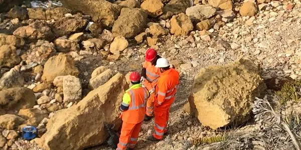 Operaris del Ministeri de Medi Ambient trituren dues roques que havien caigut a la platja d’Altafulla abans de l’estiu
